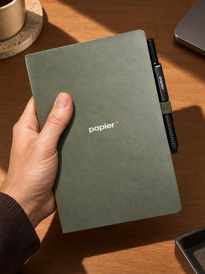 Groen notitieboekje met merklogo en een bijpassende pen met hetzelfde logo